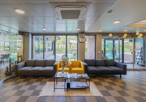 Un vestíbulo con dos sofás, una mesa de centro y vistas al exterior a través de amplias ventanas.