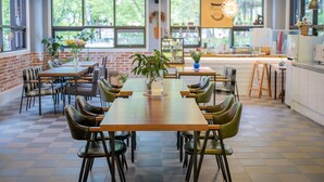 Un comedor moderno con paredes de ladrillo, ventanas amplias y una combinación de mobiliario de madera y metal.
