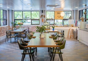 Un comedor moderno con paredes de ladrillo, ventanas amplias y una combinación de mobiliario de madera y metal.