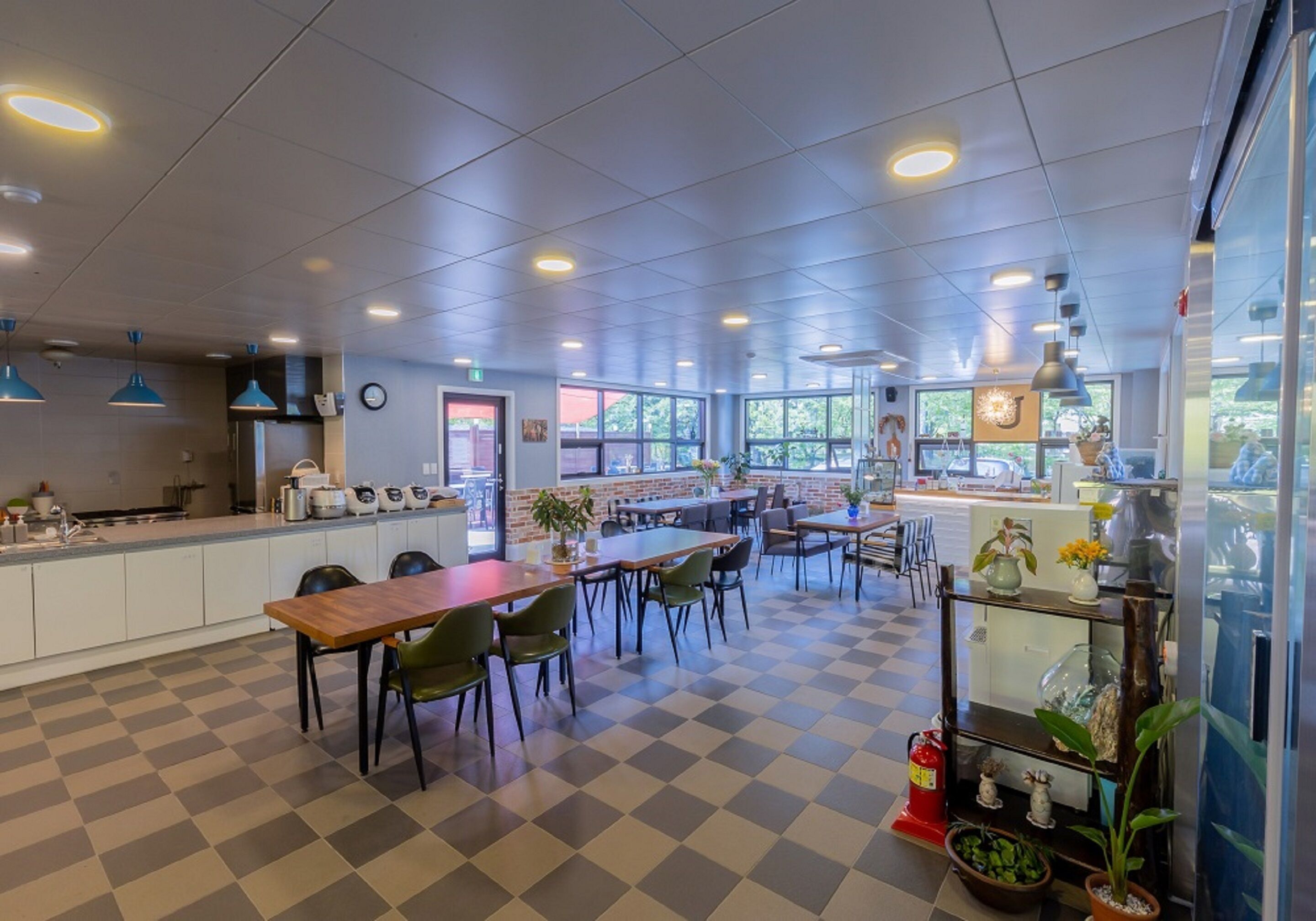 Un restaurant moderne avec un sol à carreaux, de nombreuses tables et chaises, et des luminaires suspendus.