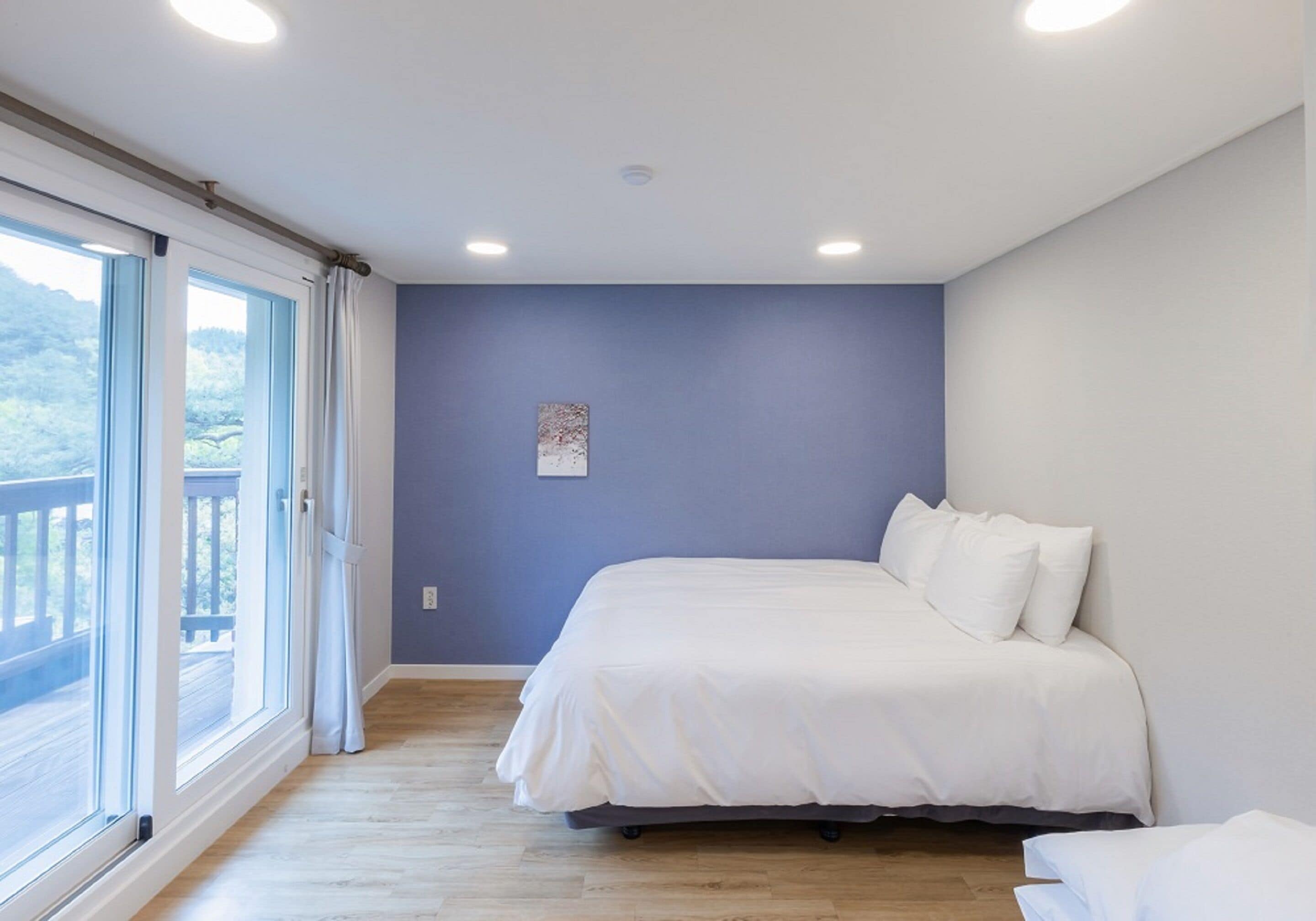 Un dormitorio con una cama grande, una ventana con cortinas y vistas al exterior.
