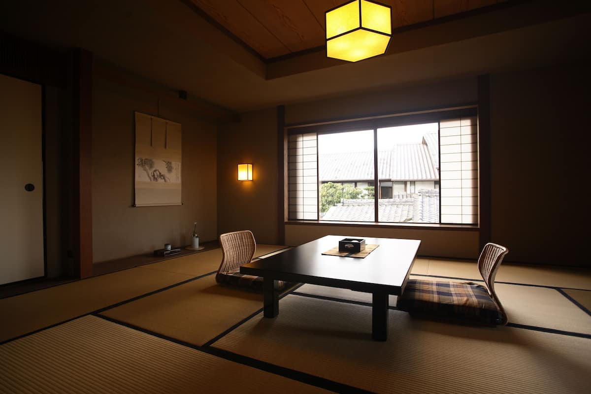 A traditional Japanese room with tatami flooring, a low table, and two cushions.