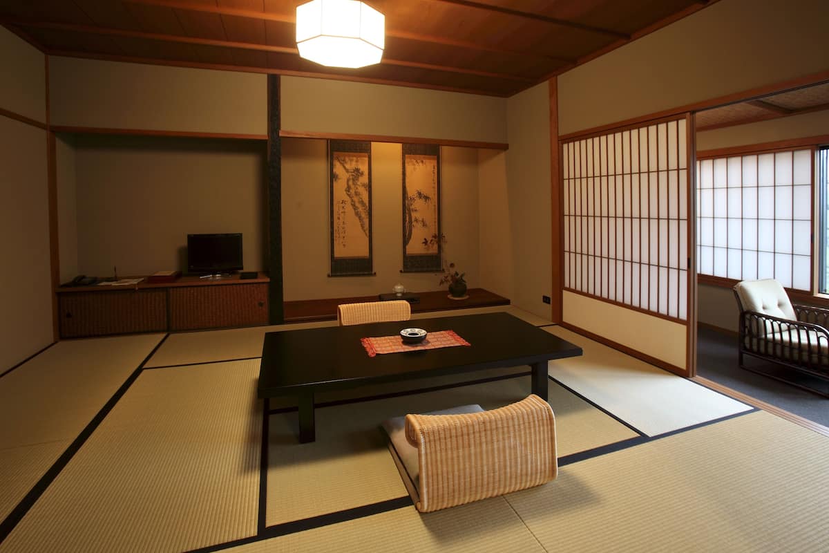 A traditional Japanese room with tatami flooring, a low table, a sofa, and sliding doors.