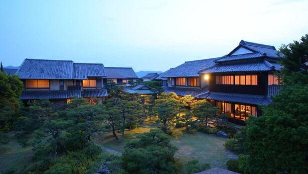 A traditional Japanese courtyard with multiple buildings, wooden walkways, and well-maintained greenery. - Yoyokaku (Karatsu)