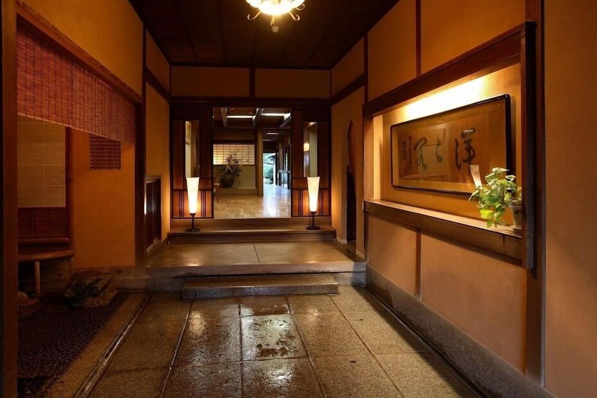 A traditional Japanese interior with a wooden floor, a reception desk, and a hanging light fixture.