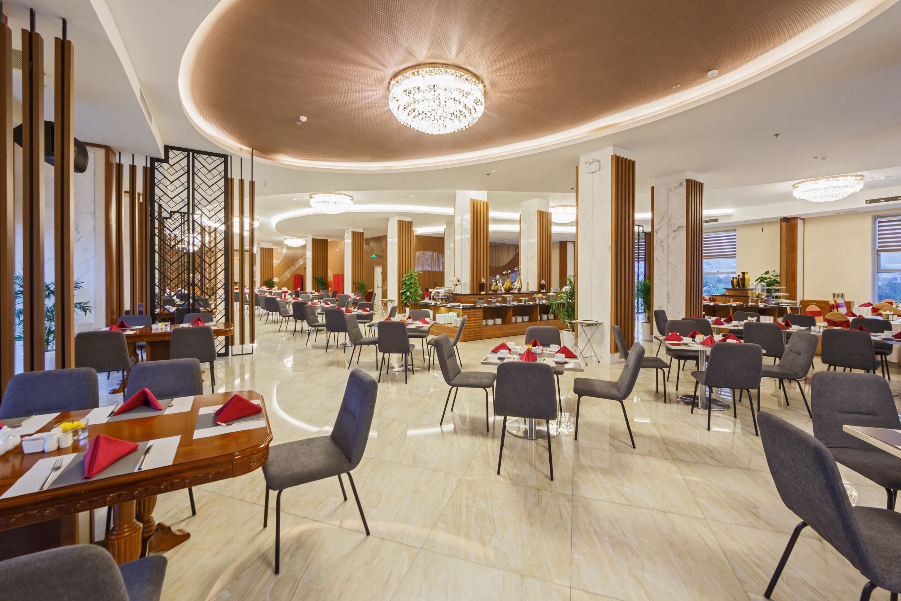 A spacious dining area with multiple tables and chairs, a central bar, and a chandelier.