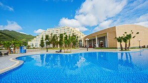 A hotel with a swimming pool, a large building with multiple floors, and a mountainous backdrop. - Muong Thanh Luxury Moc Chau (Thao Nguyen)