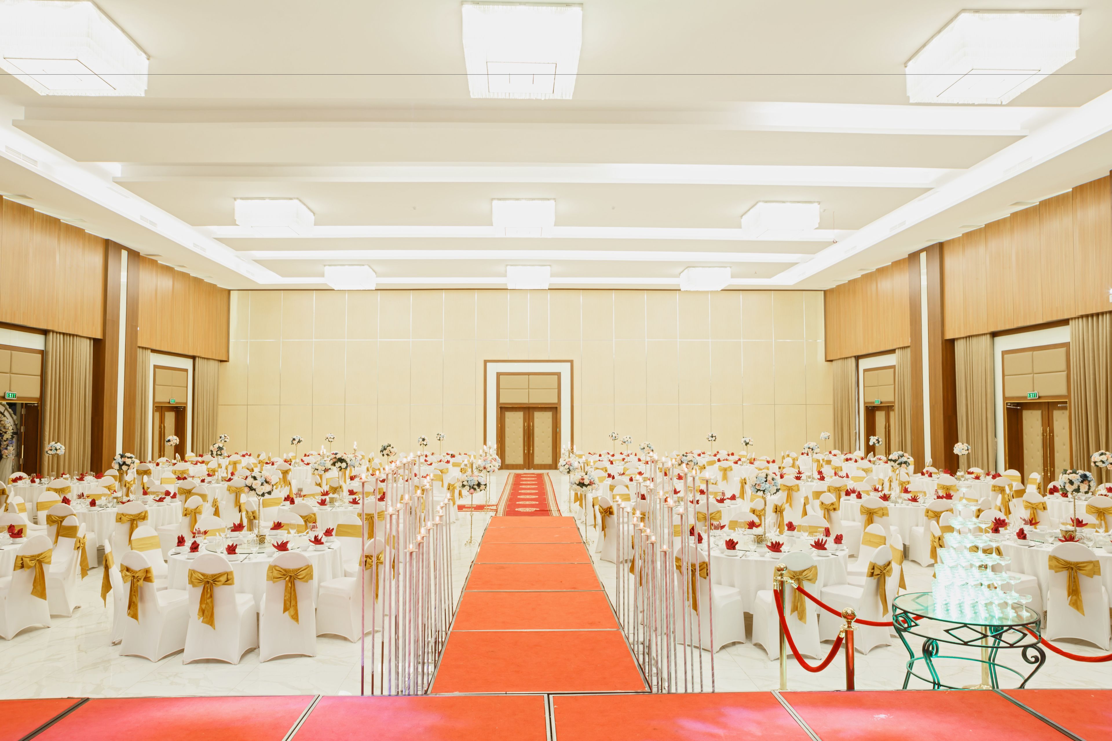 A large hall with rows of round tables, a central aisle, and a red carpet.