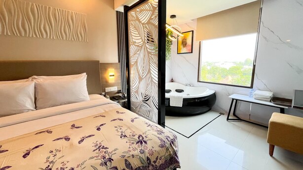 Una habitación de hotel moderna con una cama grande, una bañera redonda y un amplio ventanal con vistas.