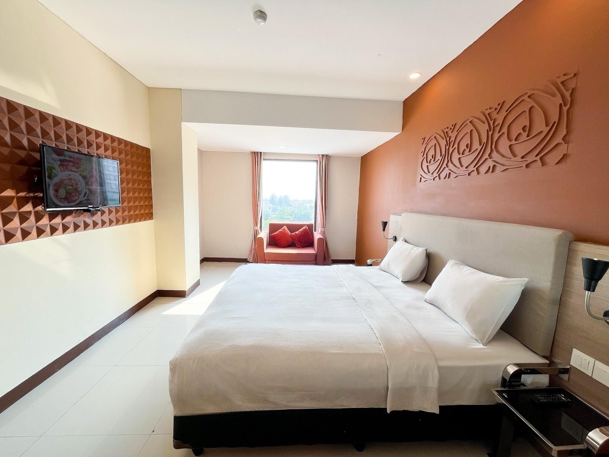 Une chambre d’hôtel avec un grand lit, un téléviseur fixé au mur et une vue sur l’extérieur.