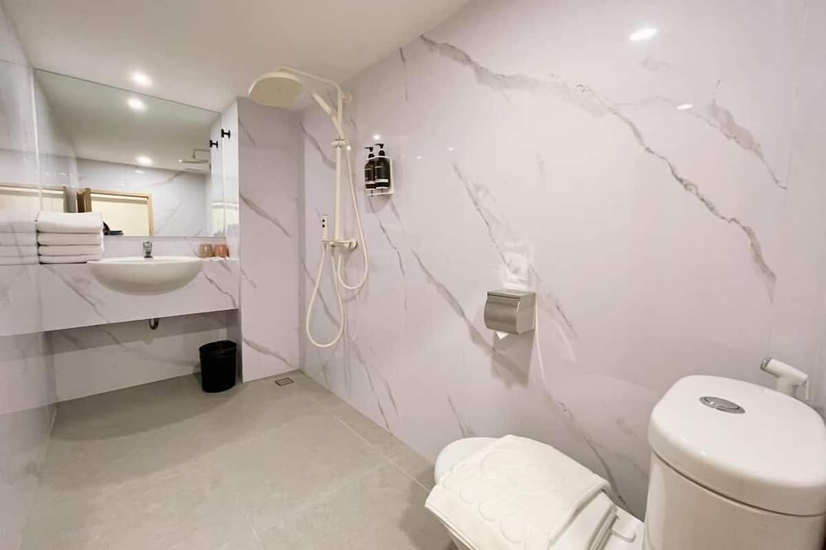 Ein modernes Badezimmer mit Marmorwaschbecken, Toilette, Dusche und Spiegel.
