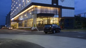 Un hotel moderno con fachada geométrica, ventanas iluminadas y un letrero llamativo en la parte superior.