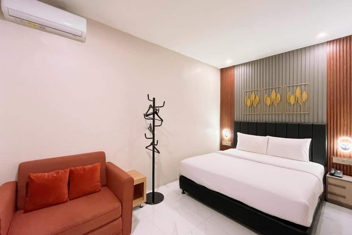 Ein Hotelzimmer mit Bett, einer Couch, einem Kleiderständer und einer Wandklimaanlage.