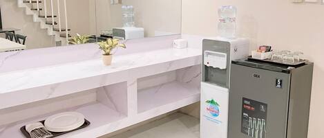 Un baño de hotel moderno con encimera de mármol, dispensador de agua, refrigerador GEA y lavamanos.