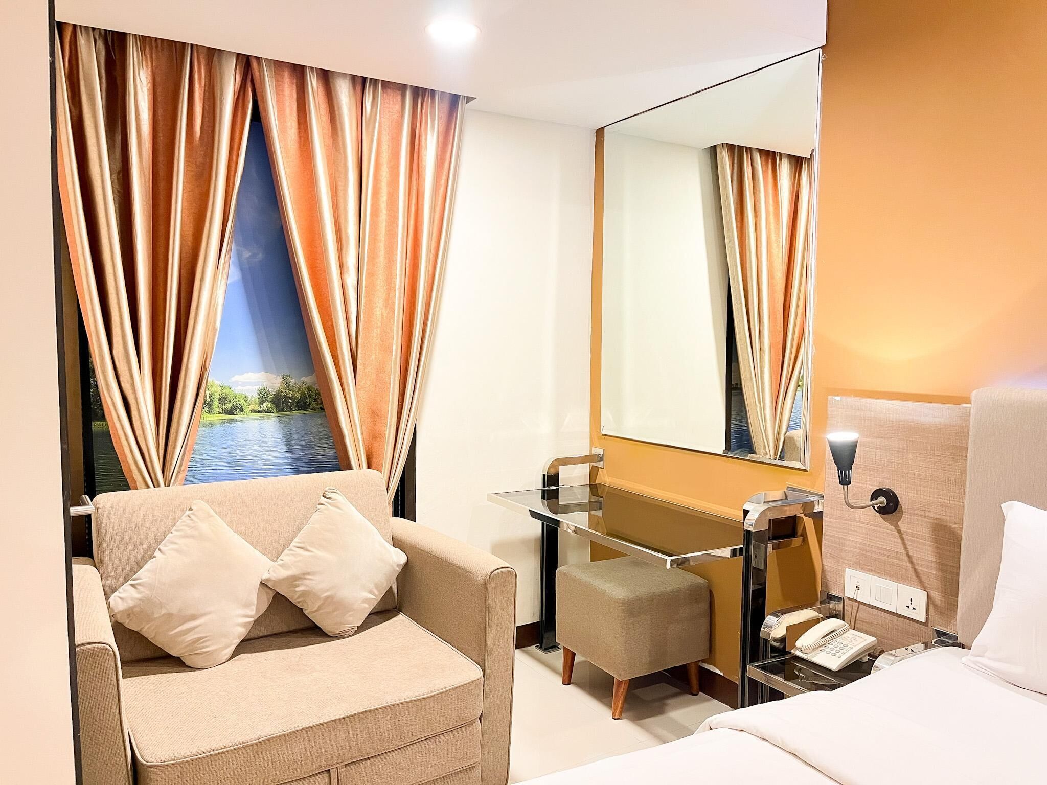 Ein Hotelzimmer mit Sofa, einem kleinen Tisch, einem Spiegel und einem Bett.