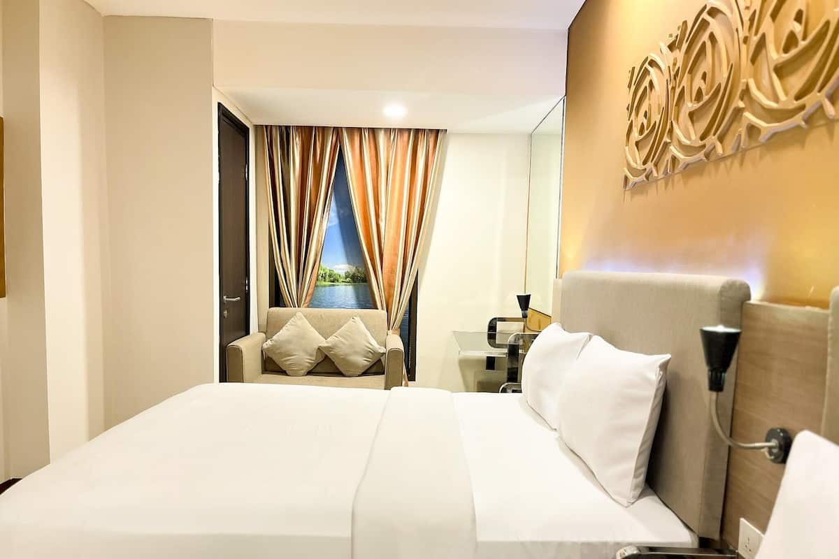 Ein Hotelzimmer mit einem großen Bett, einer Sitzecke, einem Schreibtisch und einem Wandspiegel.