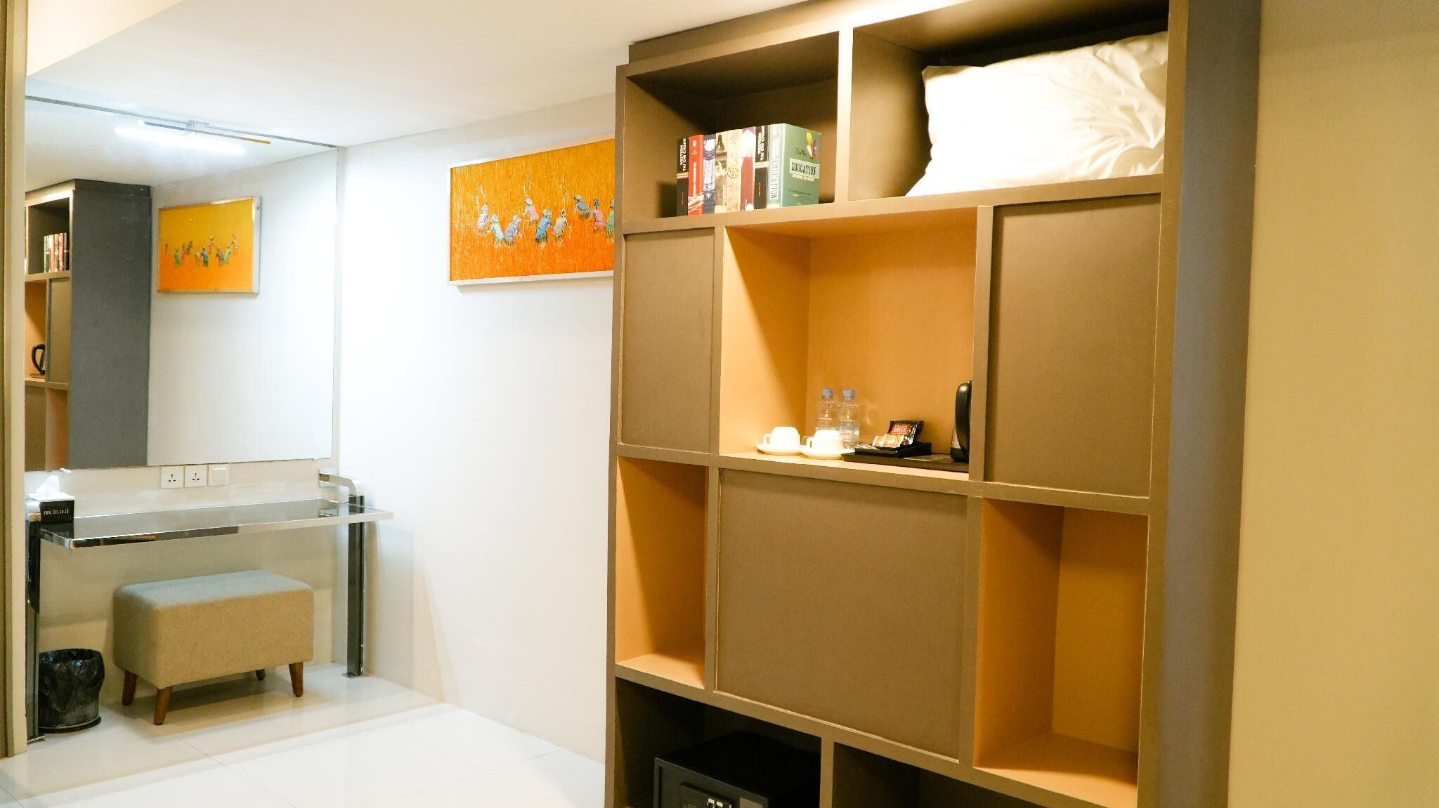 Een moderne badkamer met een wastafelmeubel, een bankje en een grote plank met boeken en toiletartikelen.