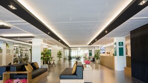 A modern lobby with a reception desk, seating area, and potted plants. - iChapter Hotel Suvarnabhumi (Bang Phli)