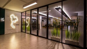 A modern interior with glass walls, indoor plants, and a geometric light installation. - iChapter Hotel Suvarnabhumi (Bang Phli)