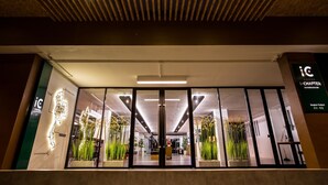 A modern hotel entrance with a wooden ceiling, large glass doors, and indoor plants. - iChapter Hotel Suvarnabhumi (Bang Phli)