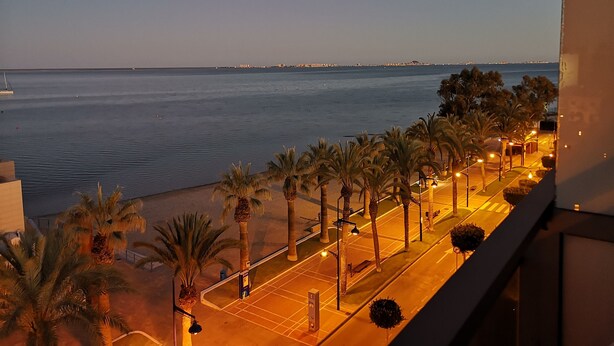 A coastal view with a calm sea, palm trees, and a well-lit street. - Hotel Ribera (San Javier)