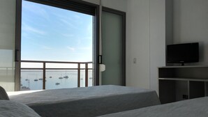 A hotel room with two beds, a TV, and a view of boats through a large window. - Hotel Ribera (San Javier)