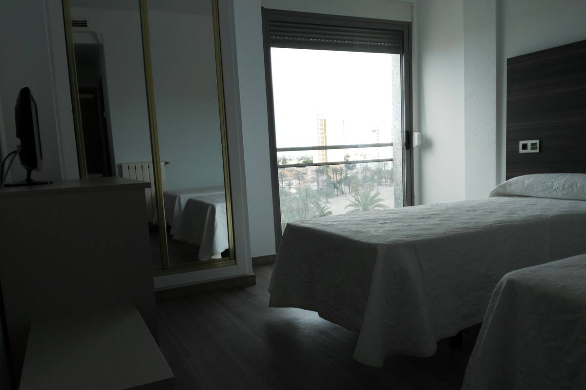 Una camera d'albergo con un letto, una scrivania e un'ampia finestra.