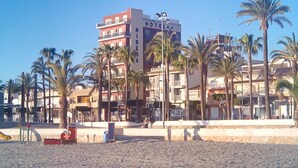 A hotel with multiple floors, palm trees in front, and a sandy beach area. - Hotel Ribera (San Javier)