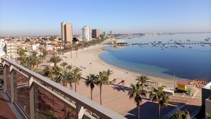 A coastal cityscape with a beach, palm trees, and a marina. - Hotel Ribera (San Javier)