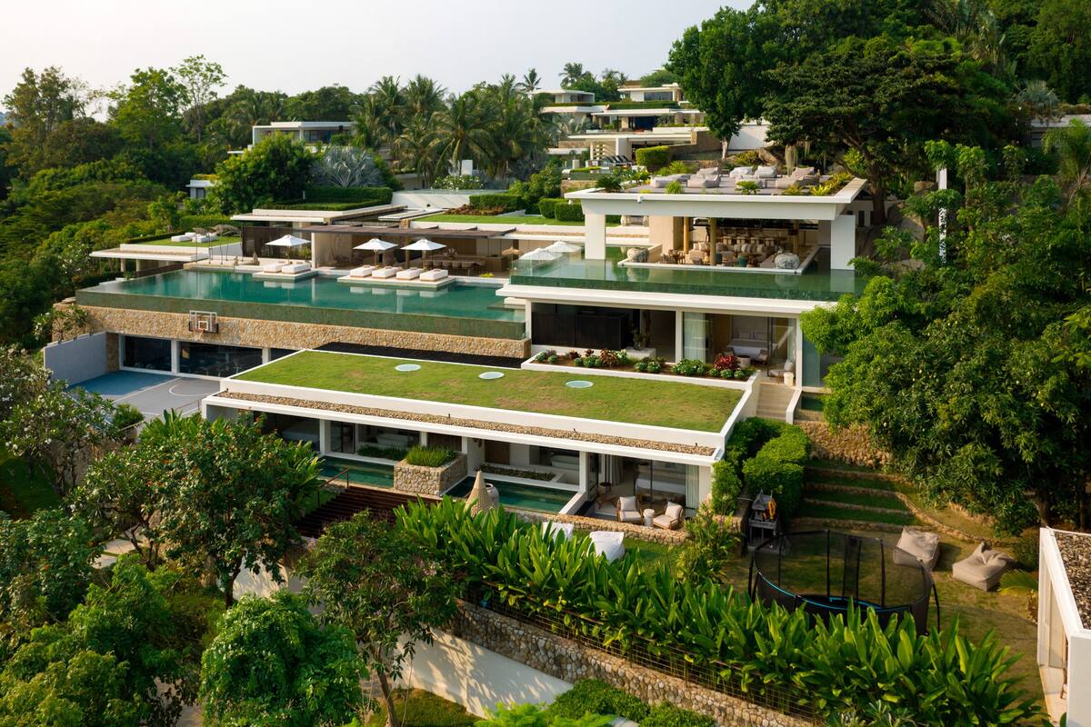 A modern resort with multiple swimming pools, lush greenery, and contemporary architecture.