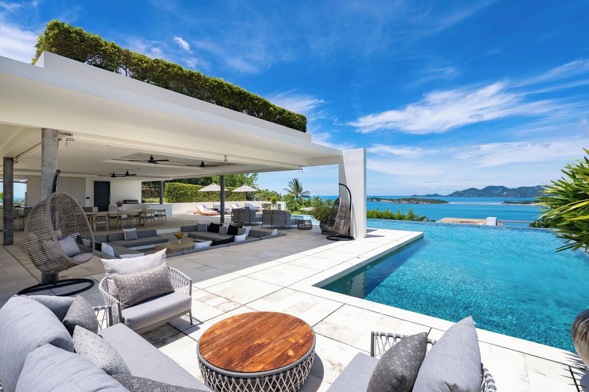 Uma área moderna com piscina ao ar livre, assentos e vista para o oceano.
