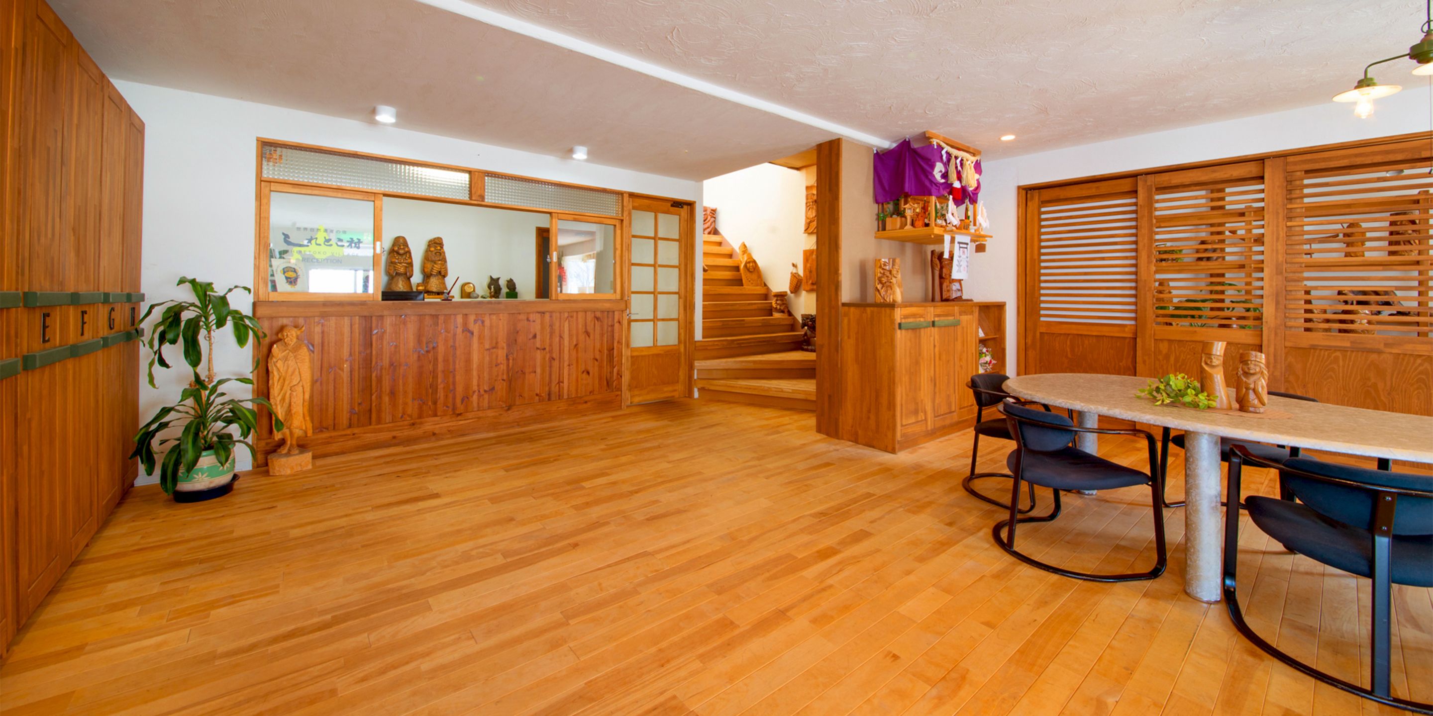 A wooden interior with a dining area, staircase, and a reception desk.