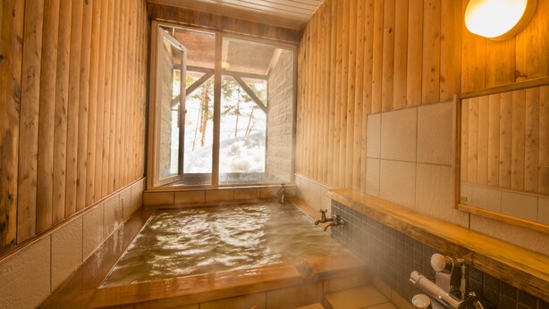 A wooden spa room with a hot tub, wooden walls, a window, and a mirror. - Shiretoko Village (Shari)
