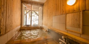 A wooden spa room with a hot tub, wooden walls, a window, and a mirror.