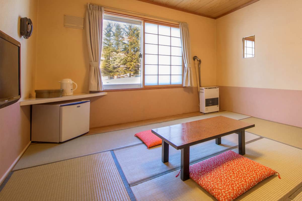 A traditional Japanese room with tatami flooring, a low table, and a small heater.