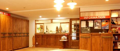 A reception area with wooden cabinets labeled with letters, a reception desk, and an information board.