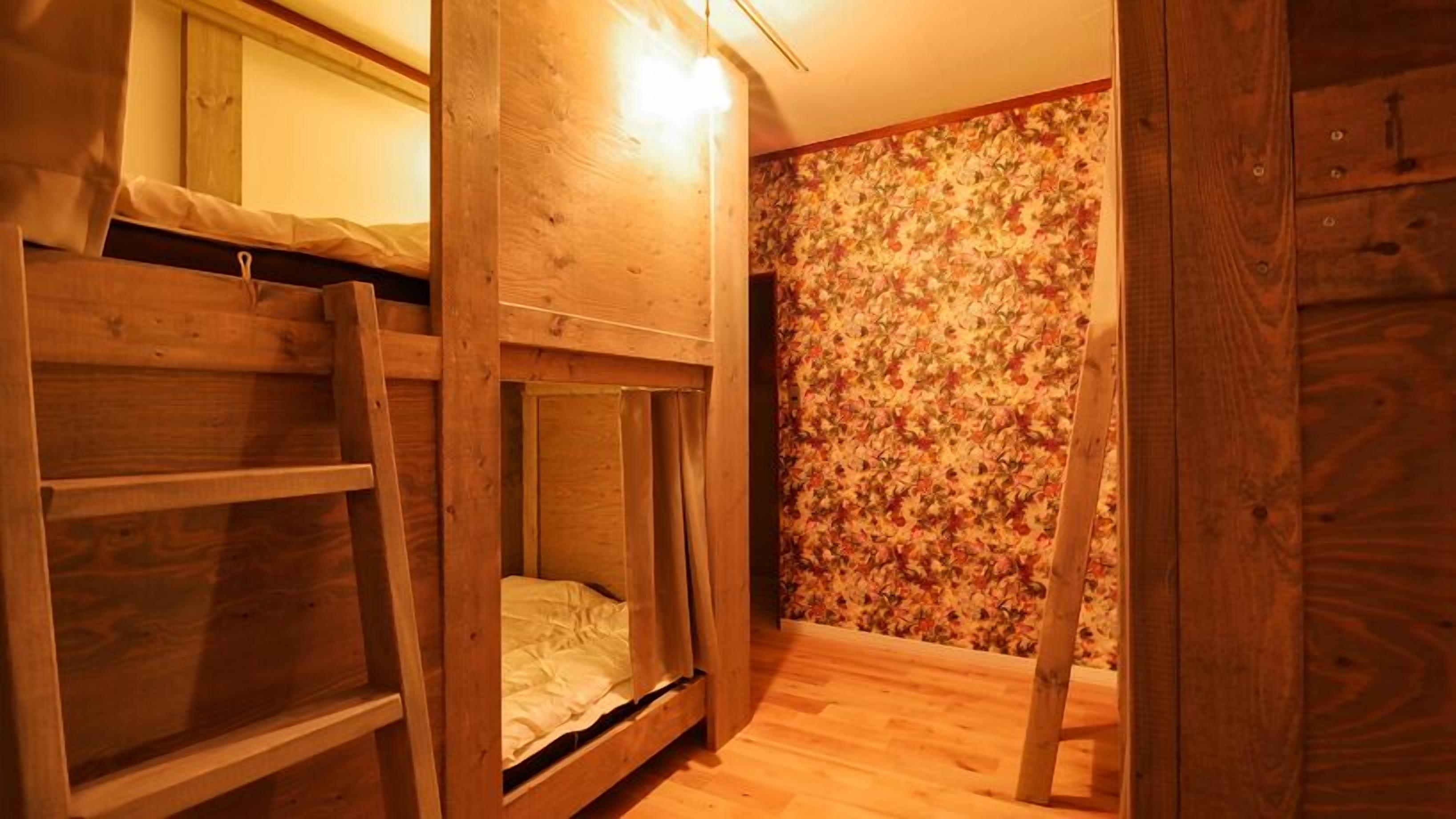 Ein Schlafzimmer mit Etagenbetten, Holzwänden und einem floralen Wandmuster.