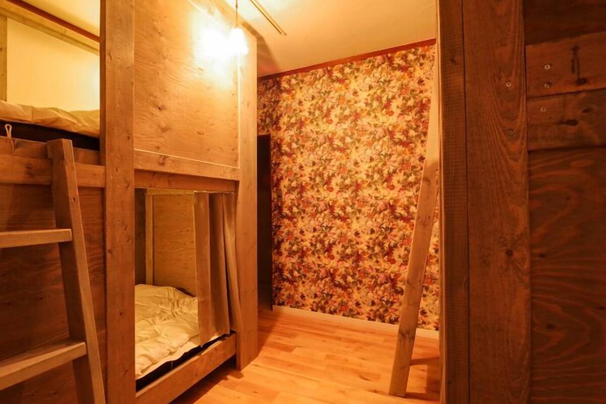 A bunk bed room with wooden walls and a floral wallpaper pattern.