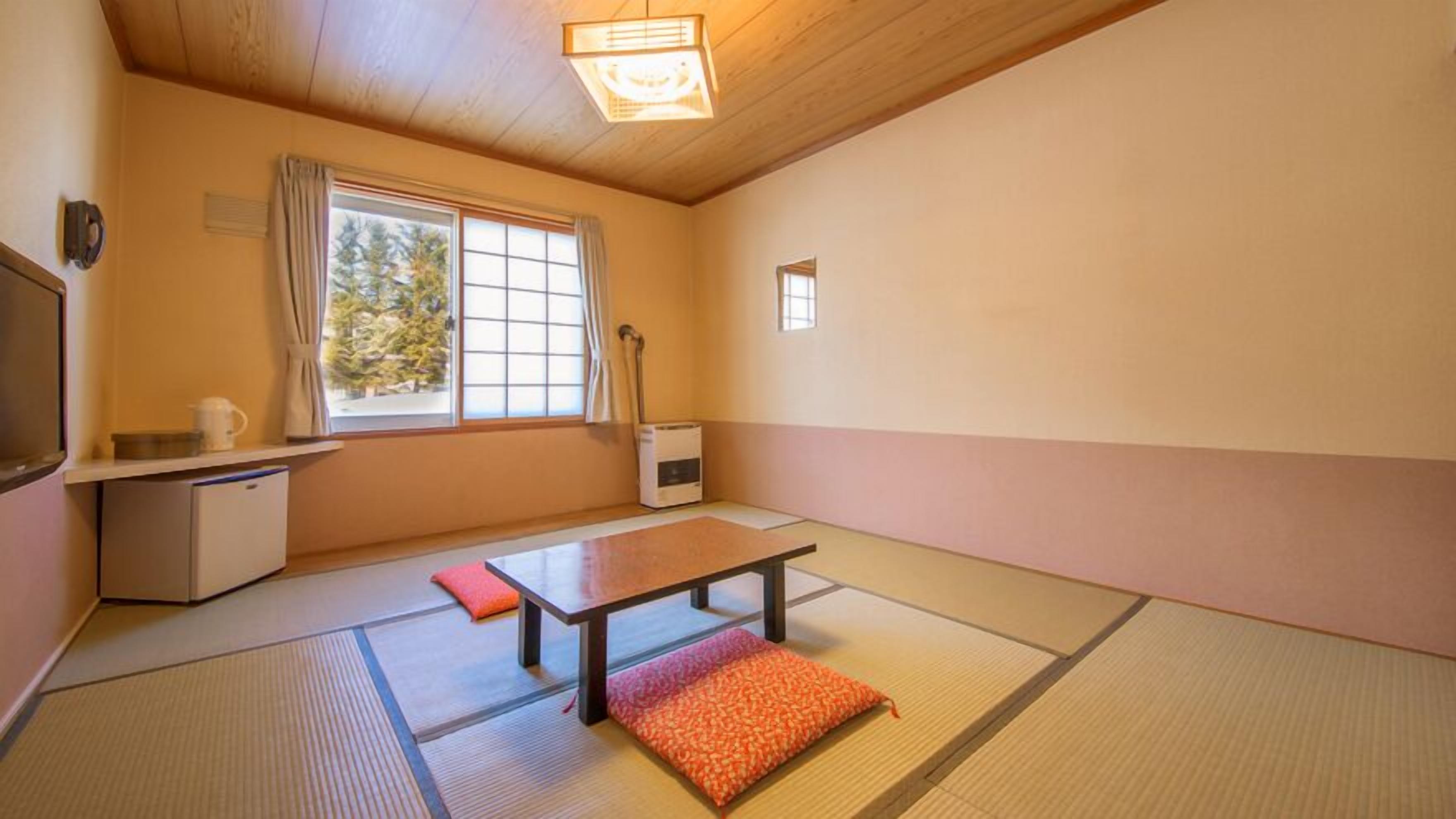 Ein traditioneller japanischer Raum mit Tatami-Böden, einem niedrigen Tisch, einer Bank, einer Heizung und einem Fenster mit Vorhängen.