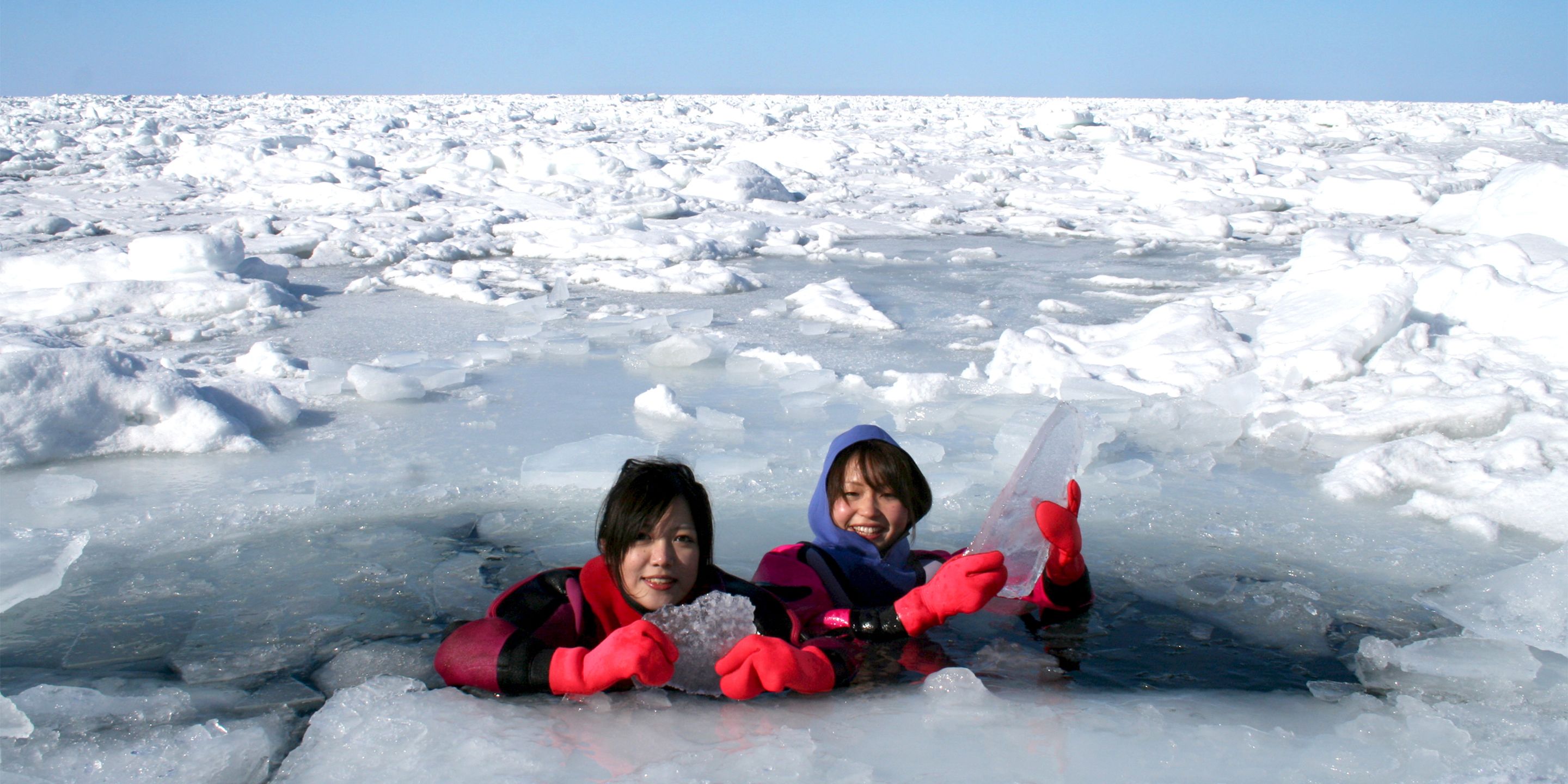 Dos personas en un paisaje nevado con formaciones de hielo.