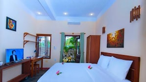 Una habitación de hotel con una cama, un escritorio con televisor, una ventana con cortinas y obras de arte en las paredes.