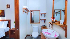 Un baño de hotel con cama, inodoro, lavabo y espejos.