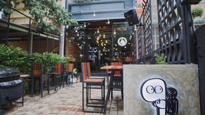 An outdoor patio area with tables and chairs, a grill, and a decorative wall with a cartoon character. - No.9 Hostel (Chiang Mai)