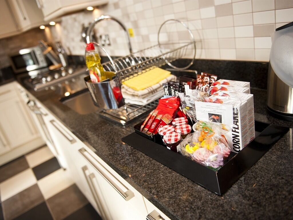 A kitchen counter with a variety of packaged food items, a bottle of olive oil, and a coffee machine.