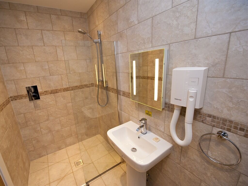 A modern bathroom with a shower, a sink, and a mirror.