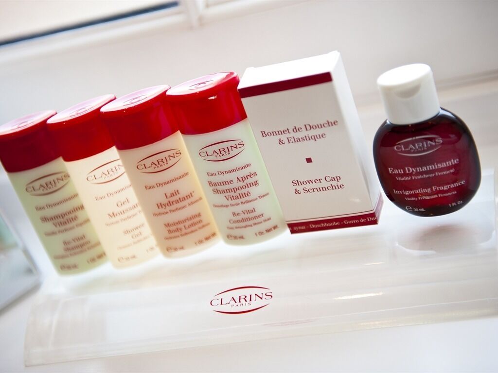 Une sélection de produits Clarins Paris, comprenant un bonnet de douche, un soin pour le corps et différents types de shampooings.