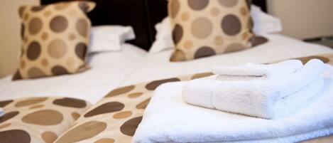 A neatly made bed with a polka dot pattern, a folded white towel, and matching pillows.