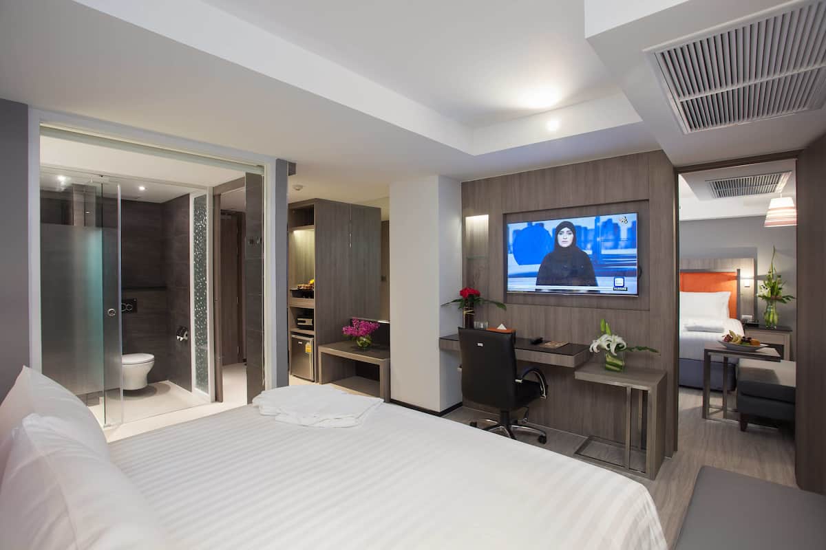 Une chambre d’hôtel moderne équipée d’un grand lit, d’un bureau avec un ordinateur, d’une télévision et d’un espace douche.