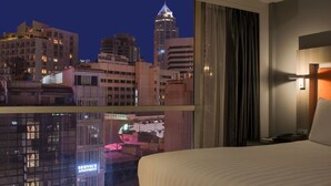A hotel room with a large window offering a city view at night, including a prominent building with a spire. - Grand 5 Hotel & Plaza Sukhumvit Bangkok (Bangkok)