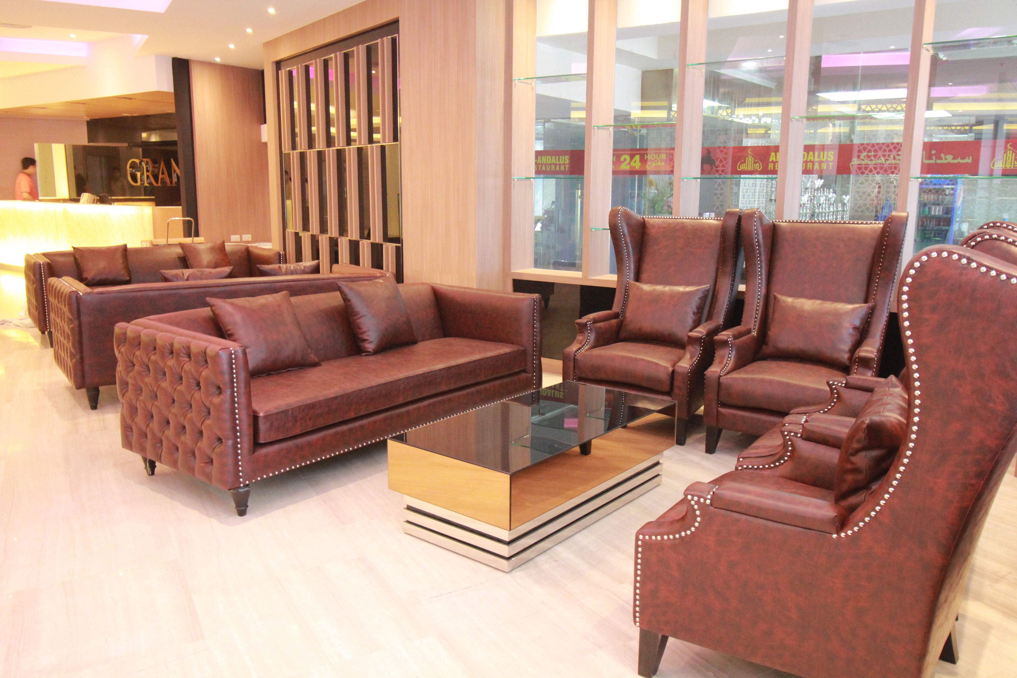 A lobby with leather sofas, a glass coffee table, and a reception desk.